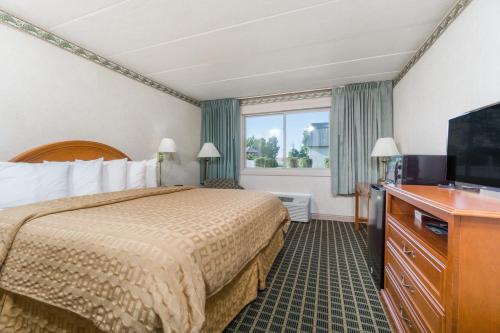 a hotel room with a bed and a flat screen tv at Days Inn by Wyndham Columbus East Airport in Columbus