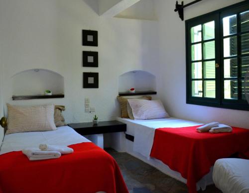 una camera con due letti con lenzuola rosse e una finestra di Regina a Kalo Chorio