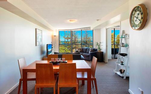 - un salon avec une table, des chaises et un canapé dans l'établissement Scarborough Beach Resort Queensland, à Scarborough