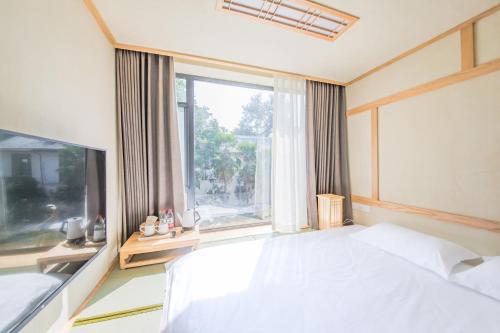 a bedroom with a large bed and a large window at Hangzhou Van Wind Inn in Hangzhou
