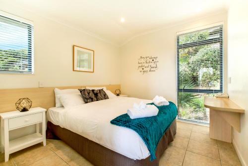 a bedroom with a bed and a window at Villa Rosa at Palm Beach by Waiheke Unlimited in Palm Beach
