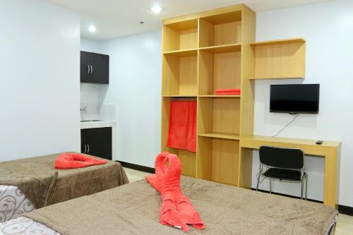 um quarto com 2 camas, uma televisão e uma secretária em Global 88 Apartelle em Cebu