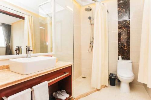 a bathroom with a sink and a shower and a toilet at Hua Qi Kaiserdom Hotel Zhongshan Road St Michael's Cathedral and Zhanqiao Pier Qingdao in Qingdao