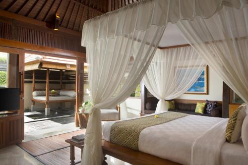 um quarto com uma cama com cortinas e uma televisão em Ubud Village Hotel em Ubud