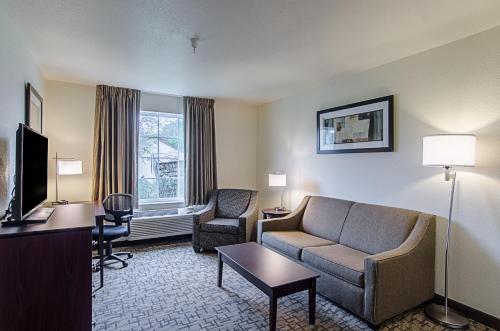 a hotel room with a couch and a chair and a tv at Cobblestone Inn & Suites - Guernsey in Guernsey