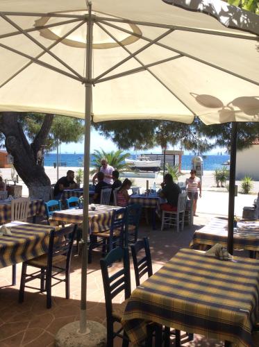 a group of people sitting at tables under an umbrella at Marina in Nikiti