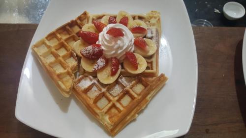 Un plato blanco con gofres con fresas y crema batida en Ella 360, en Ella