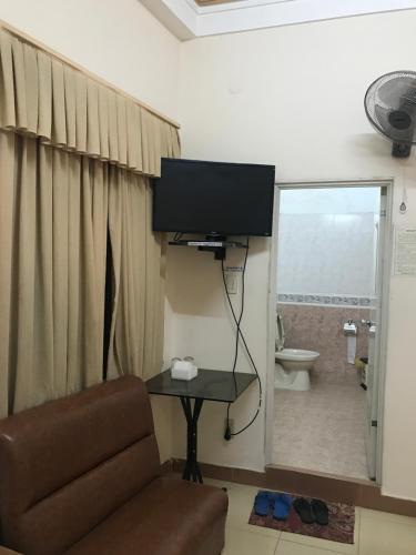 Sala de estar con silla y TV en la pared en My Anh Guest House en Dalat