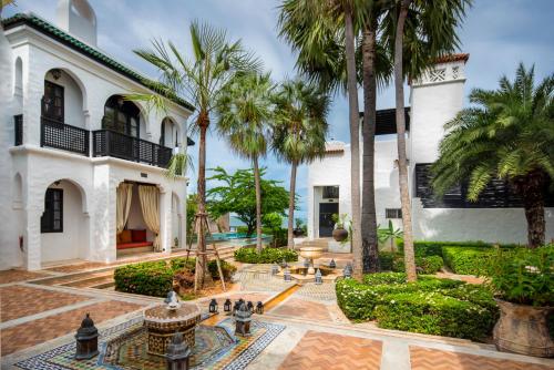 - une vue sur l'extérieur d'une maison avec des palmiers et une fontaine dans l'établissement Villa Maroc Resort, à Pran Buri