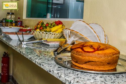 ein Tisch mit einem Kuchen auf einer Theke mit Obst in der Unterkunft Chalés de Peroba in Maragogi