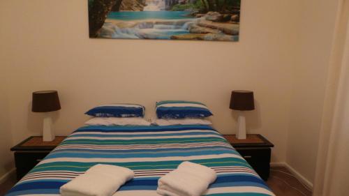 a bed with blue and white pillows and a painting at Casa Bella in Tamworth