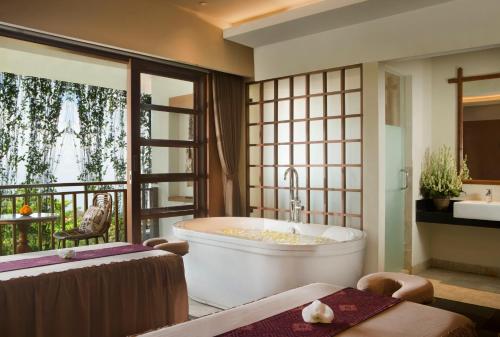 a bathroom with a large tub and a balcony at Ubud Village Hotel in Ubud