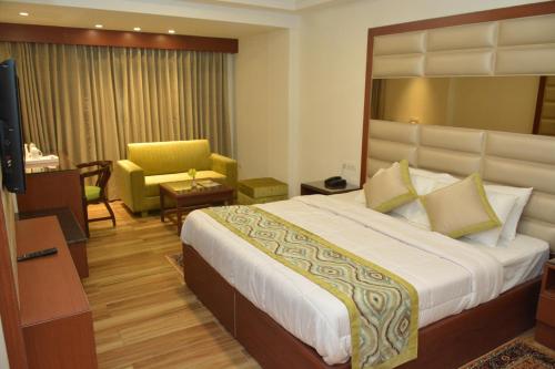 a hotel room with a large bed and a chair at Hotel Ambica Katra in Katra