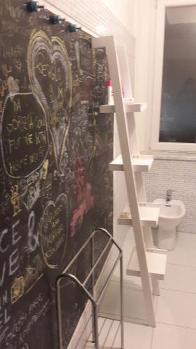 a bathroom with a wall covered in graffiti next to a toilet at Centrum Rooms in Cagliari
