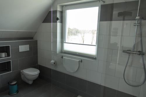 a bathroom with a shower and a toilet and a window at Villa-Meehr in Bantikow