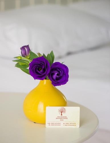 a yellow vase with purple flowers in it at Two Seasons Boutique Hotel Baku in Baku