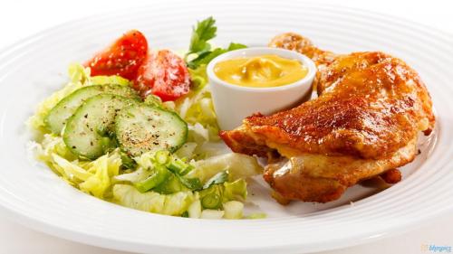 a white plate of food with chicken and salad at Transit Airport B&B in Dar es Salaam