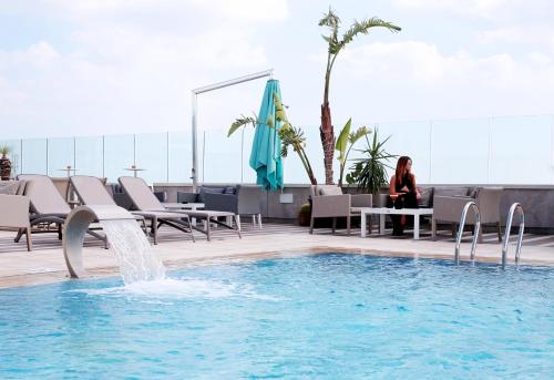 a woman sitting at a table next to a swimming pool at Radisson Hotel Sfax in Sfax