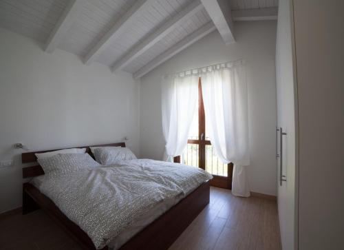 biała sypialnia z łóżkiem i oknem w obiekcie Villetta Pastura w mieście Cissano