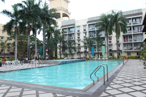 a large swimming pool in a building with palm trees at East Ortigas Mansions by MA in Manila