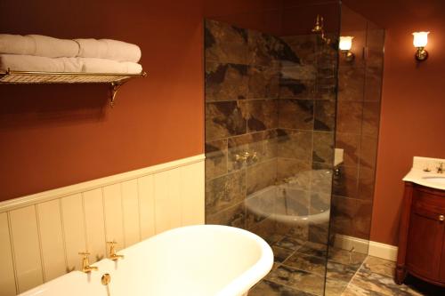 a bathroom with a tub and a shower and a sink at The Tasmanian Inn in Hobart