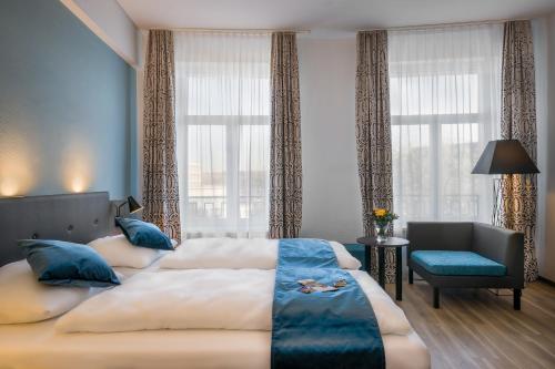 a bedroom with two beds and a chair and windows at Hotel Ruf in Pforzheim