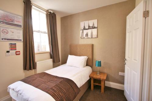 a small bedroom with a bed and a window at New County Hotel & Serviced Apartments by RoomsBooked in Gloucester