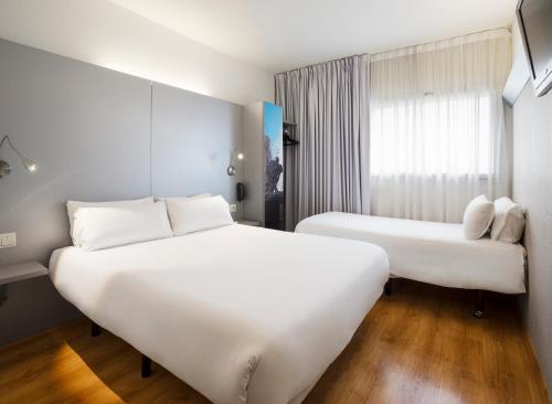 a hotel room with two beds and a window at B&B HOTEL Figueres in Figueres