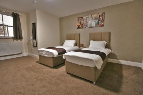two beds sitting in a room withermottermott at New County Hotel & Serviced Apartments by RoomsBooked in Gloucester