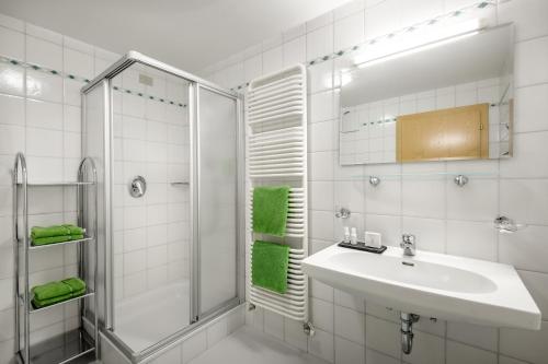 La salle de bains blanche est pourvue d'un lavabo et d'une douche. dans l'établissement Residence Bondì, à Colfosco