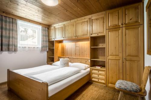 a bed in a room with wooden cabinets and a chair at Residence Bondì in Colfosco