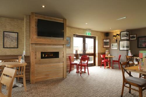 a restaurant with a fireplace and tables and chairs at Spring River Ebbsfleet by Marston's Inns in Gravesend