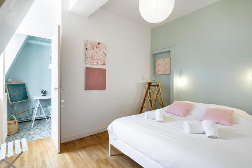 een slaapkamer met een wit bed met roze accenten bij Ty Paradis by Cocoonr in Rennes