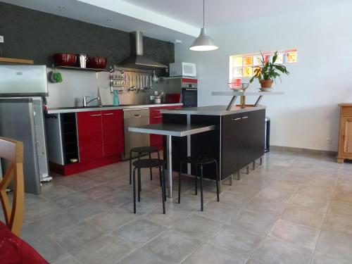 une cuisine avec des placards rouges et une table noire dans l'établissement La maison verte, à Agon-Coutainville