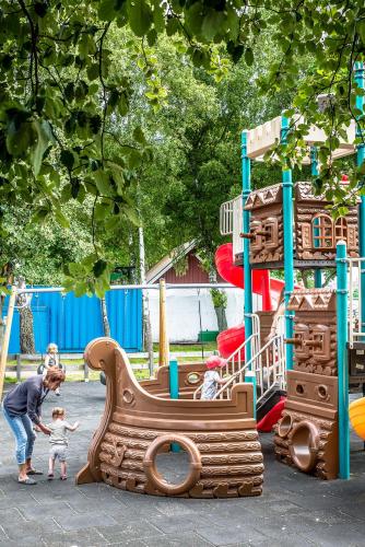 a woman and a child playing on a playground at Dragsö Camping & Stugby in Karlskrona