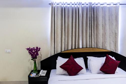 een slaapkamer met een bed met rode kussens en een raam bij Skyla Service Apartments - Gachibowli in Hyderabad