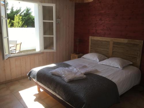 a bedroom with a large bed with a window at L'Avocette in Le Bois-Plage-en-Ré