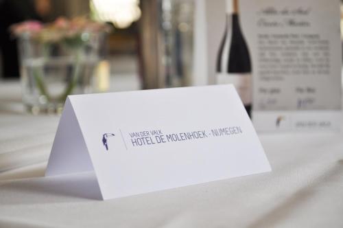 a white card on a table with a bottle of wine at Van der Valk Hotel De Molenhoek-Nijmegen in Molenhoek