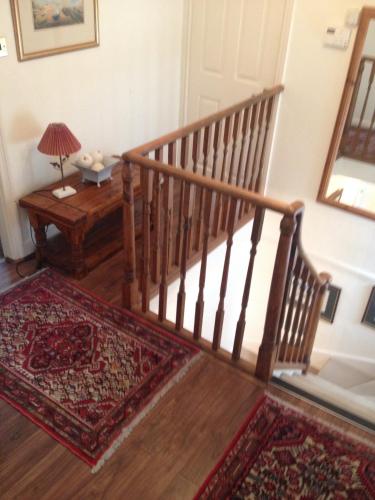 a wooden staircase with a rug and a table with a lamp at Southford House (Room Only) in Dartmouth