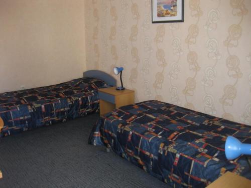 a hotel room with two beds and a lamp on a table at Hotel Astoria in Burgas