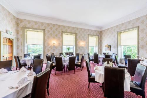 - une salle à manger avec des tables, des chaises et des fenêtres dans l'établissement Owston Hall Hotel, à Doncaster