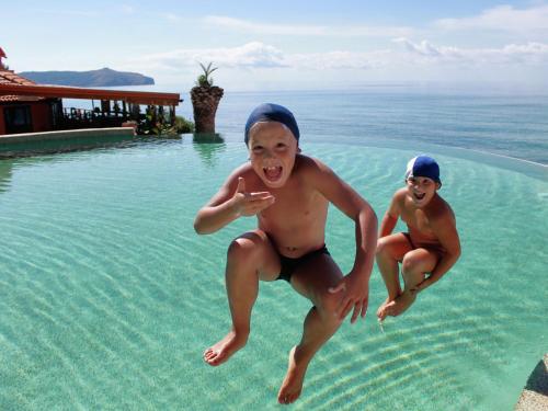 ピショッタにあるResort Baia del Silenzioの二人の若者がスイミングプールに飛び込む