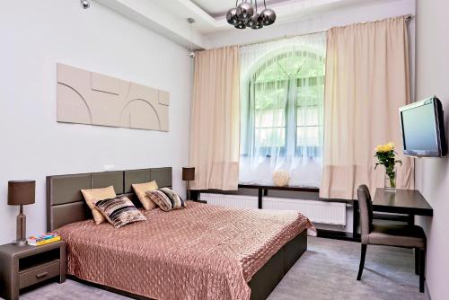 a bedroom with a bed and a desk and a tv at Rezydencja Eger in Kazimierz Dolny