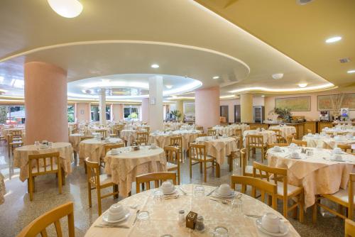 ein Esszimmer mit Tischen und Stühlen sowie weißer Bettwäsche in der Unterkunft Hotel Oasis in Alghero