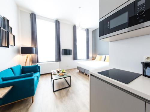 a living room with a blue couch and a bed at Urban Suites Brussels Schuman in Brussels