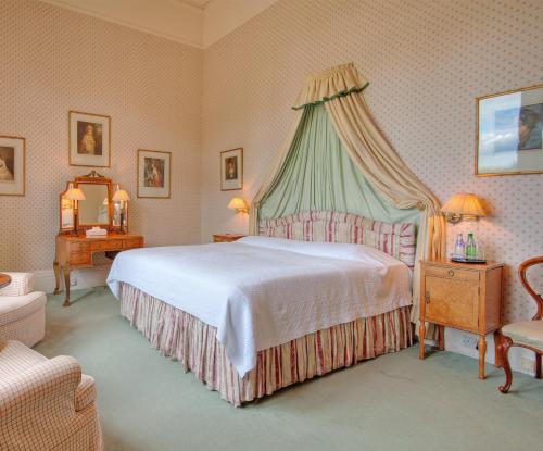 a bedroom with a large bed with a canopy at Tillmouth Park Country House Hotel in Duddo
