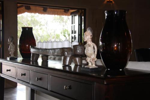 a table with vases and a statue on top of it at Vuyani Safari Lodge in Hoedspruit