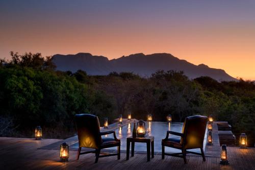 a deck with two chairs and a table with candles at Vuyani Safari Lodge in Hoedspruit