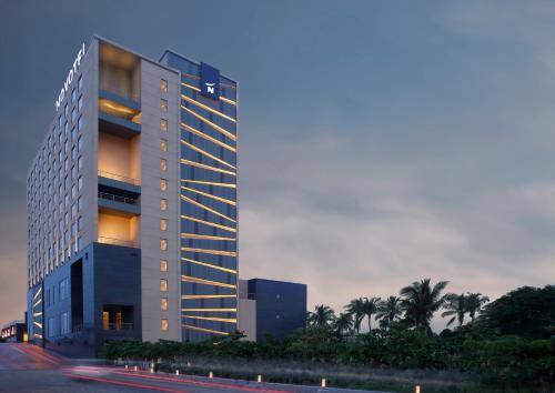 a tall building with lights on in front of a street at Novotel Chennai OMR in Chennai