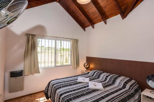 1 dormitorio con cama y ventana en Posta Suites Apart - Los Reartes en Los Reartes